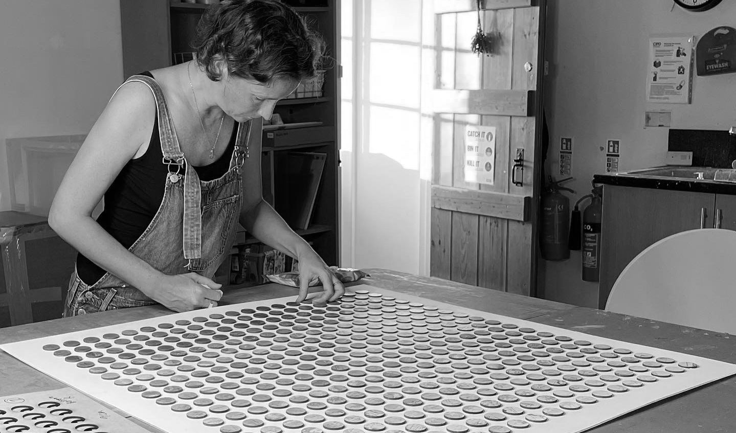 Amelia Coward in her studio working on a map dots artwork